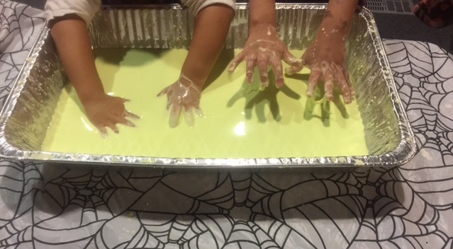 Children dipping their hands in the green goo, a mixture of cornstarch, water and food coloring