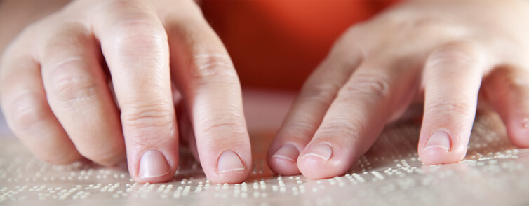Close-up photograph of a child's hands tracking a line of braille.