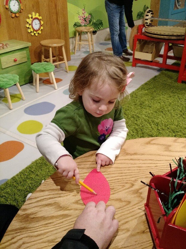 A toddler develops fine motor skills by drawing with a pencil.
