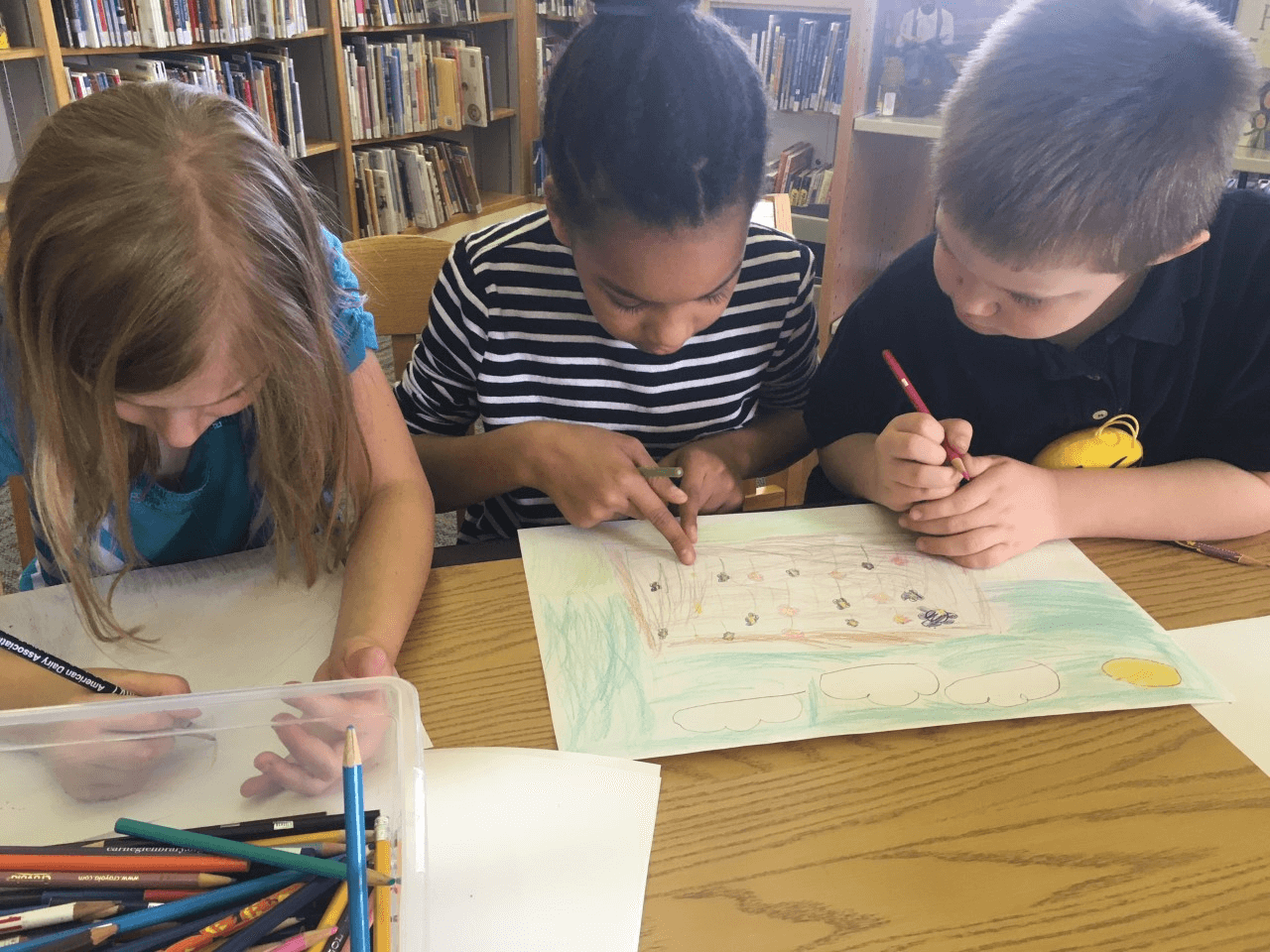 Three homeschool students draw with colored pencils togeher at CLP - Main.