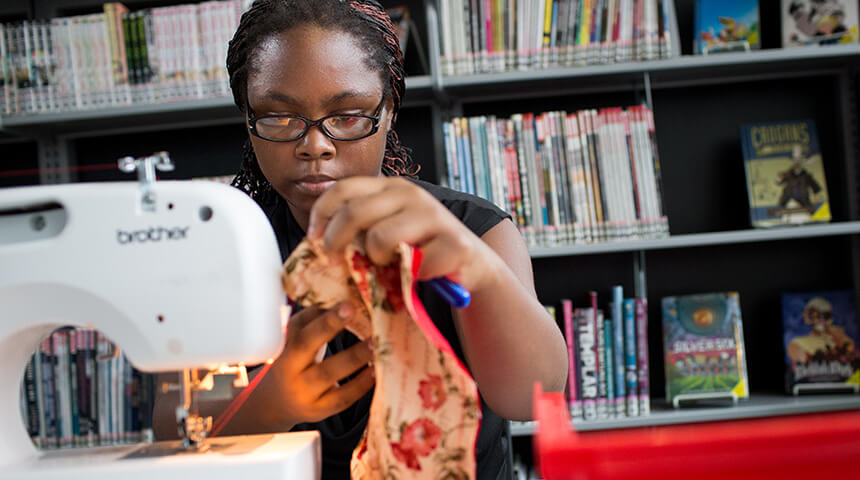 teenager using a sewing machine in the library
