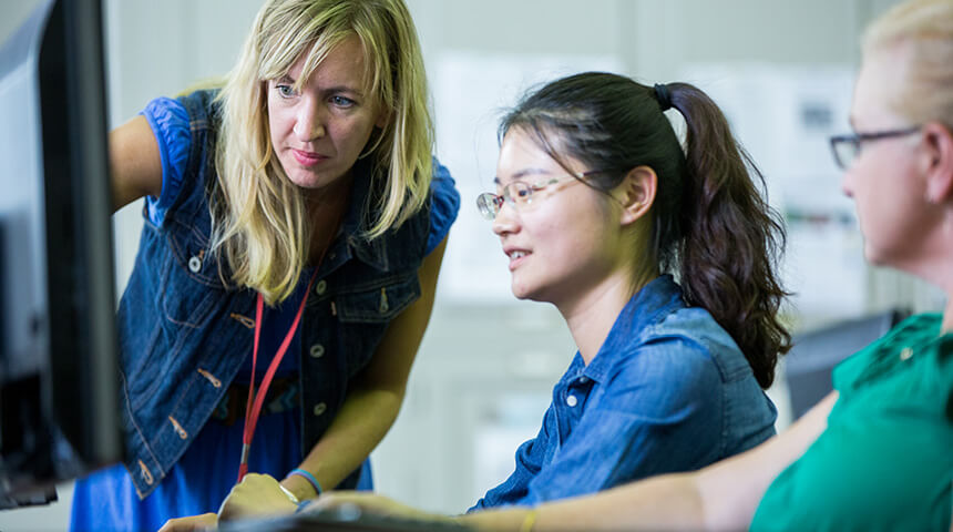 Librarian helping two adults on a computer