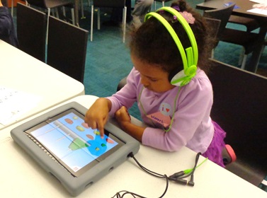 a younch child wearing bright green headphones plays on a digital tablet