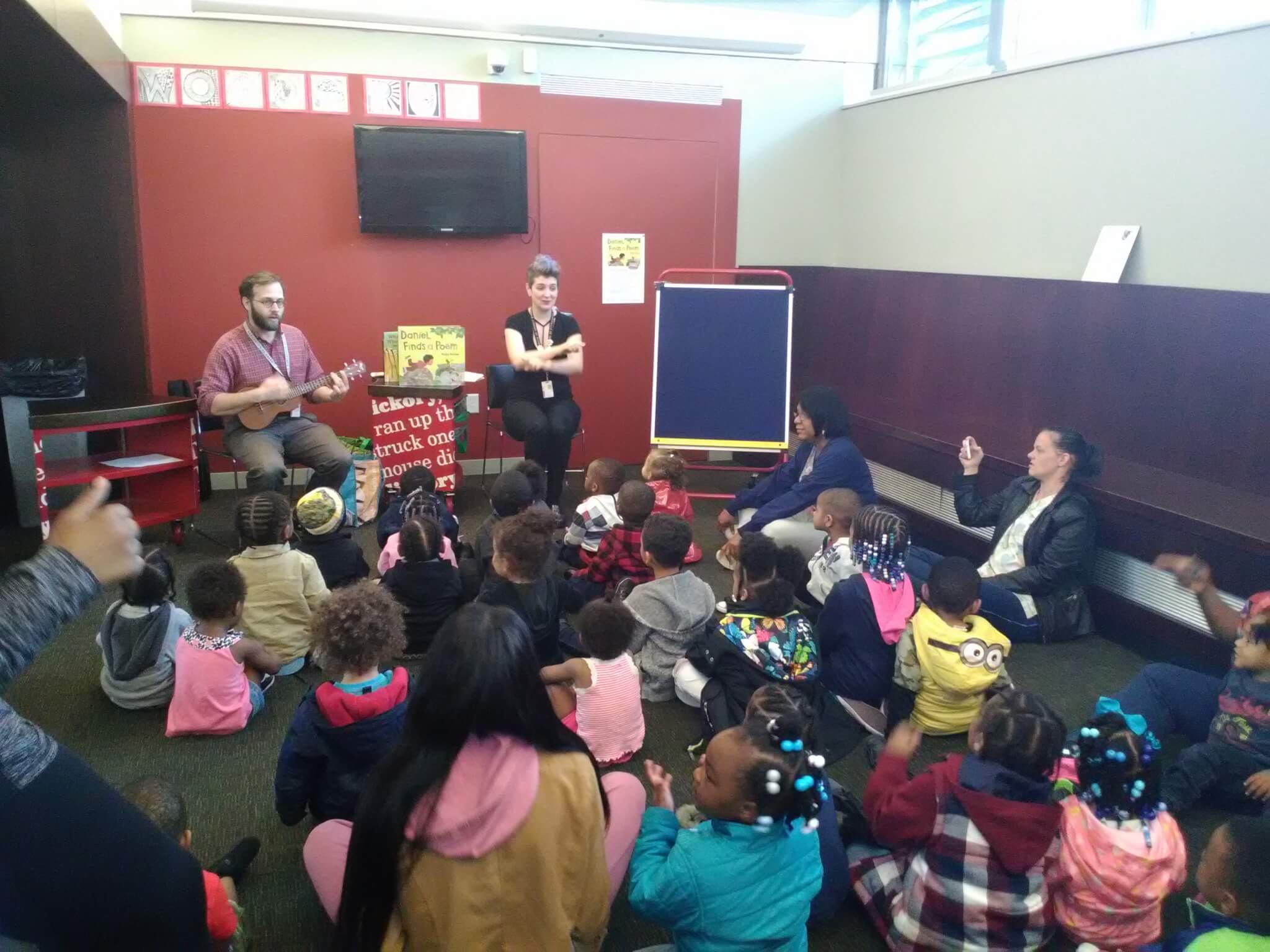 Two librarians lead large group of children in storytime