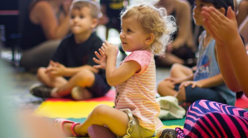 Toddler girl smiling and clapping at library storytime