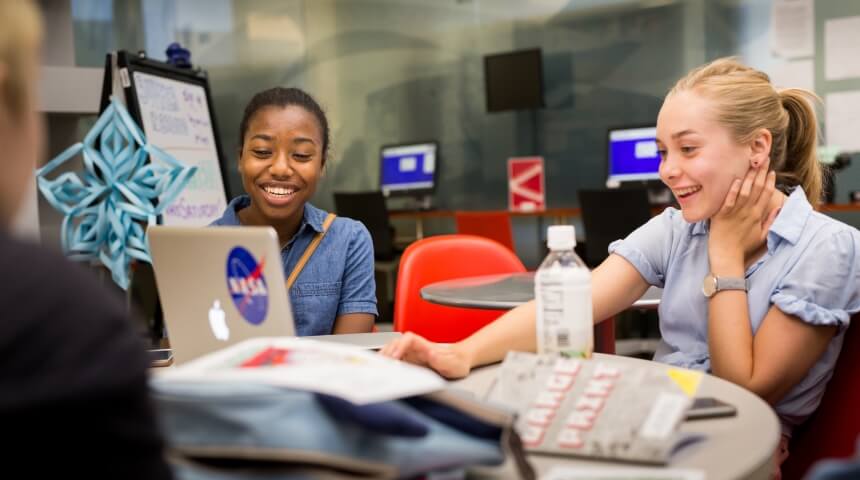 Two teens working at computers in the library