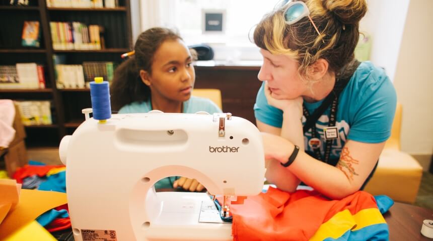 Teen specialist helps a teen at a sewing machine