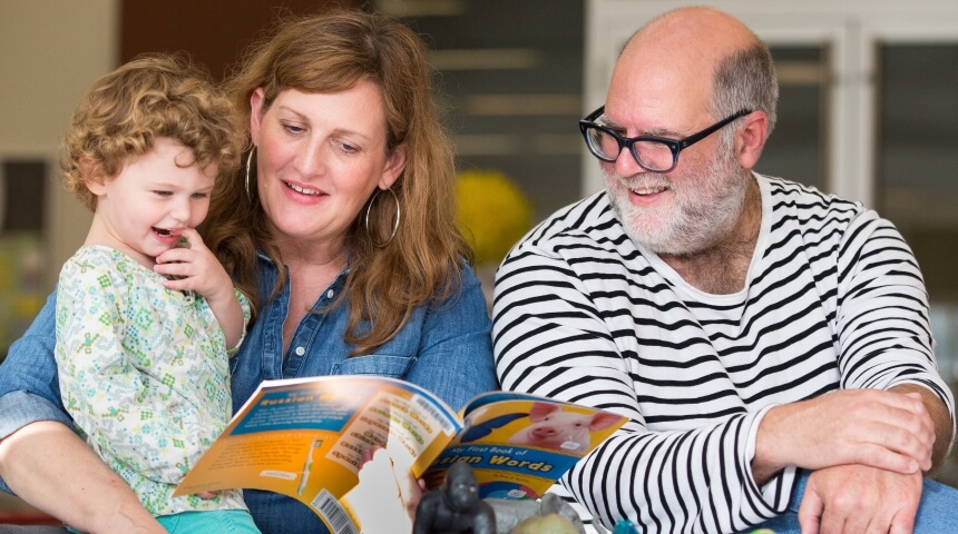 Parents read with their child at the library