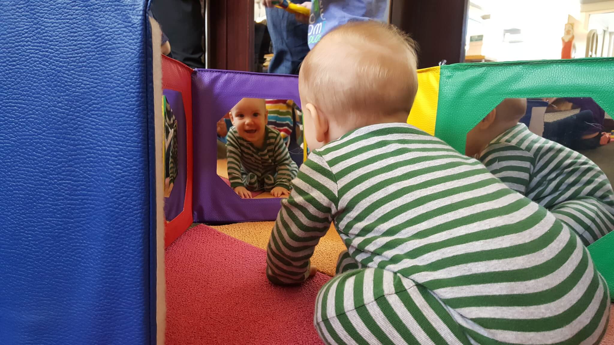 baby looks at themselves in mirror toy