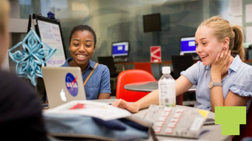 Two teens working at computers in the library