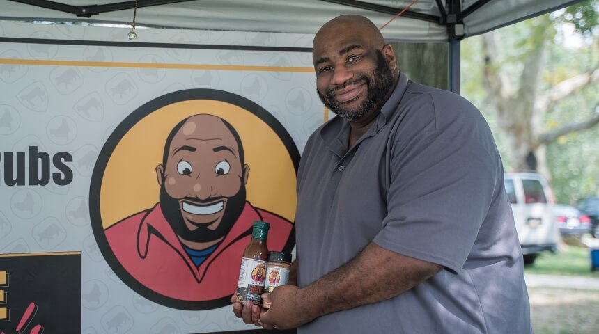 412 BBQ owner Jamal Etienne-Harrigan shows off his sauces in his tent at a farmers' market
