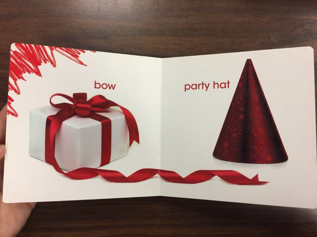 Two-page spread from the book Red by Nicole Pristash. On the left-hand page is a photograph of a white present wrapped with a red bow, and on the right-hand page, a shiny red party hat.