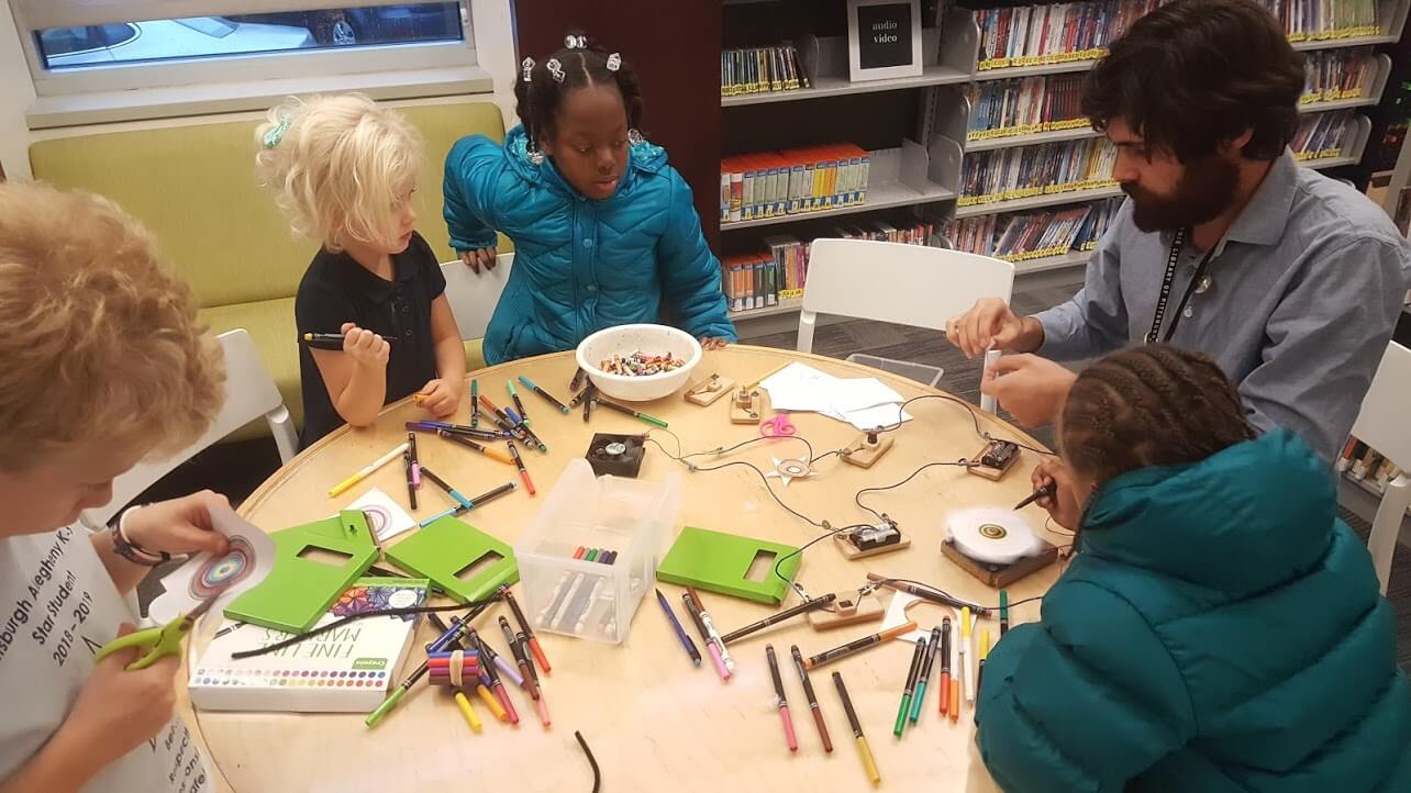 A librarian colors and works on a project with four children