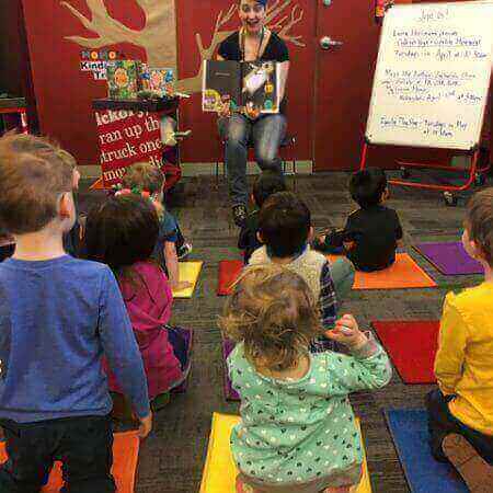 A librarian reads a book to eight kids during a storytime program at the library