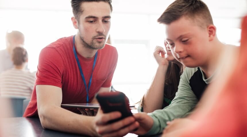 Teacher and student look at a mobile device together.