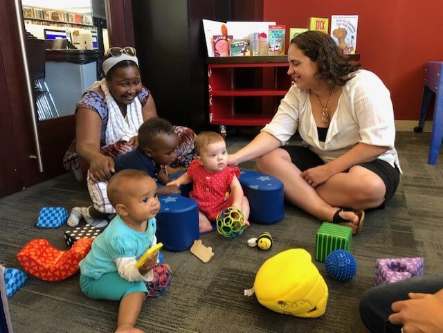 Two mothers play with their babies in the library