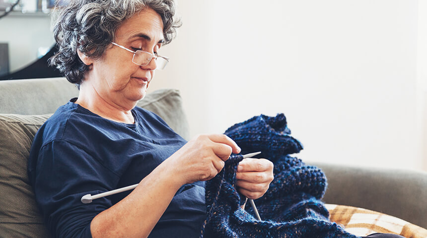 An adult knitting a blue scarf