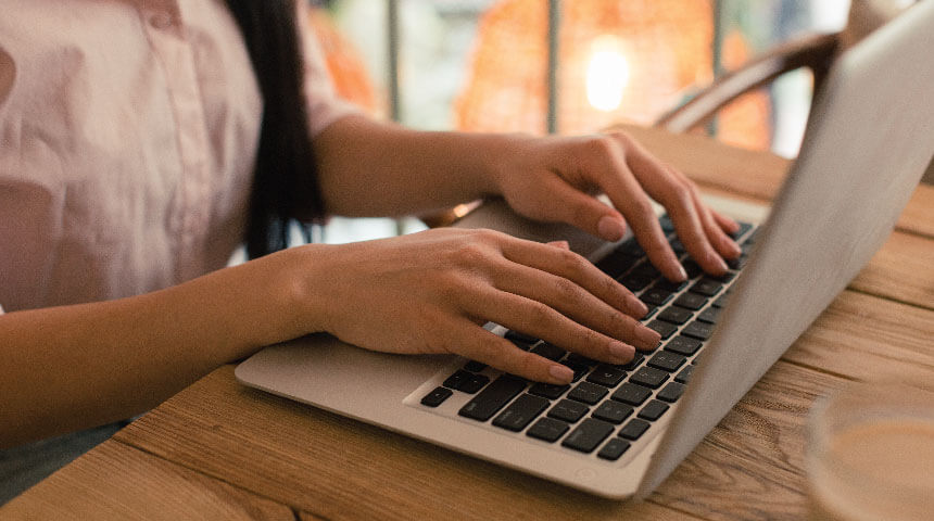 Person seated at table typing on laptop