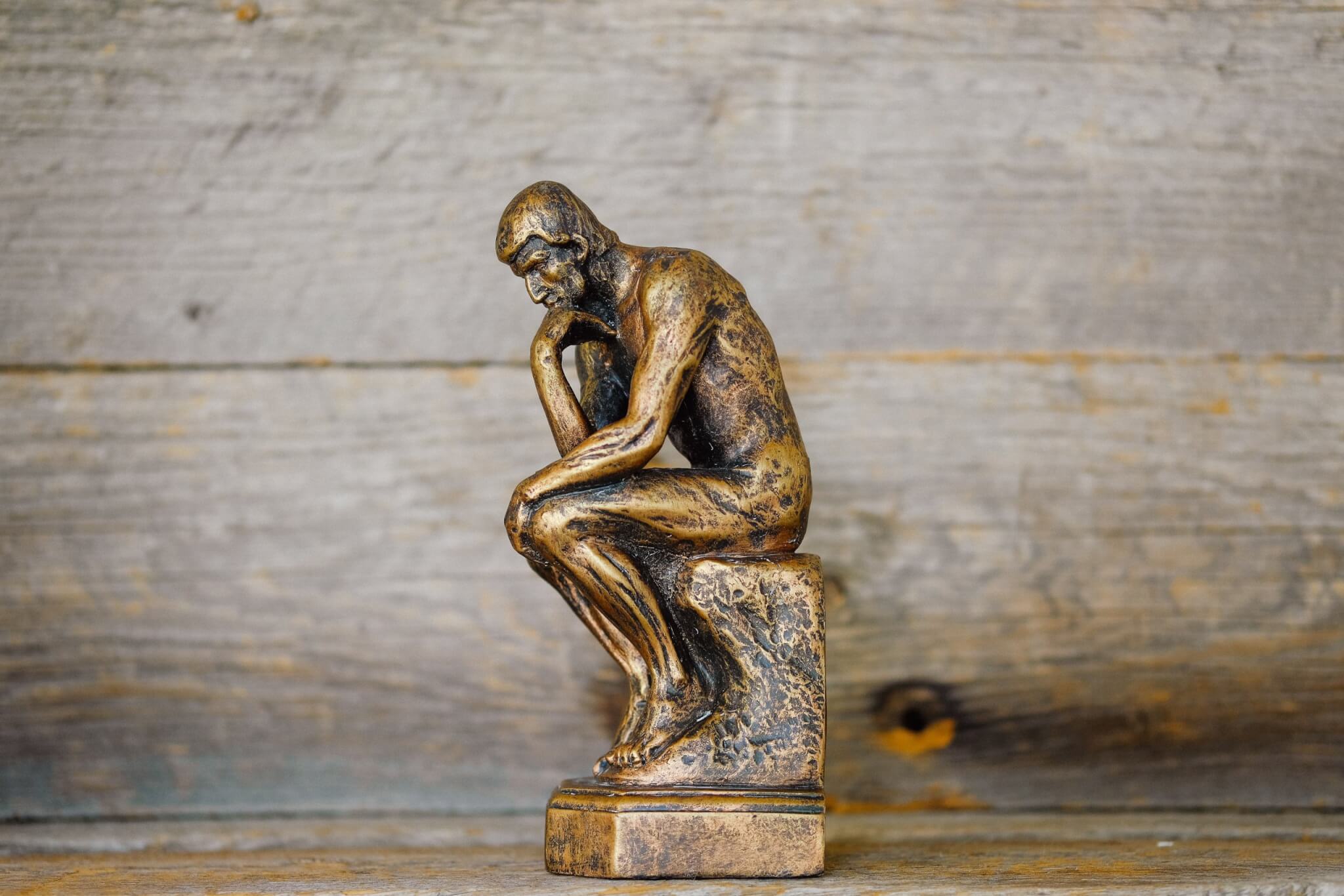 Small bronze statute of "The Thinker," a pensive person sitting