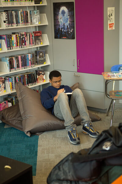 Teen reading on a giant pillow in the Teen Space at CLP - East Liberty.