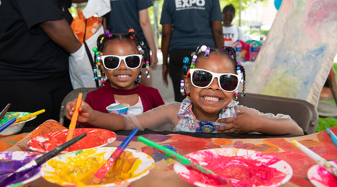 Two children in matching sunglasses painting at Summer Reading Extravaganza.