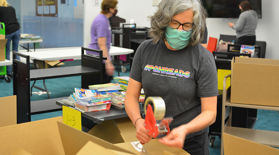 CLP librarian packing a box full of books.