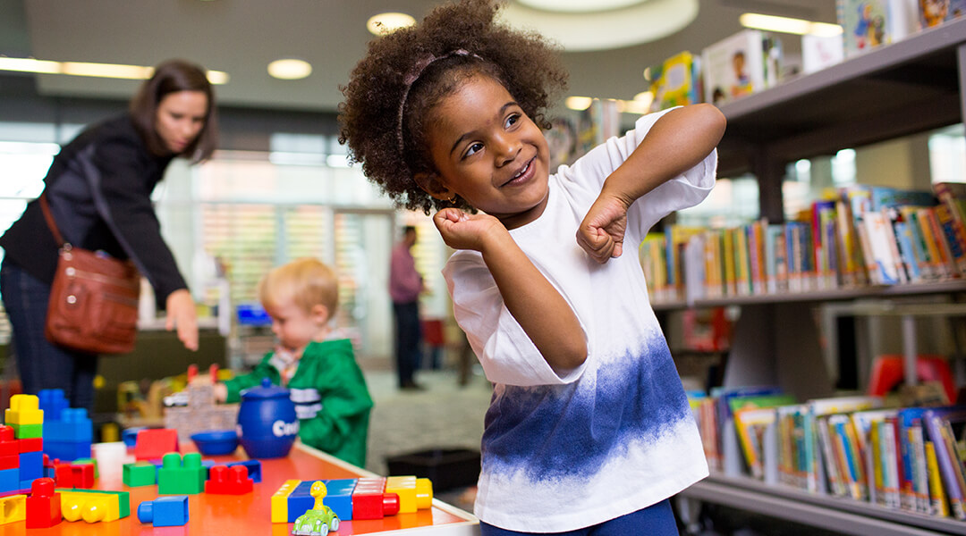 Child dancing next to toys in Children's Department.