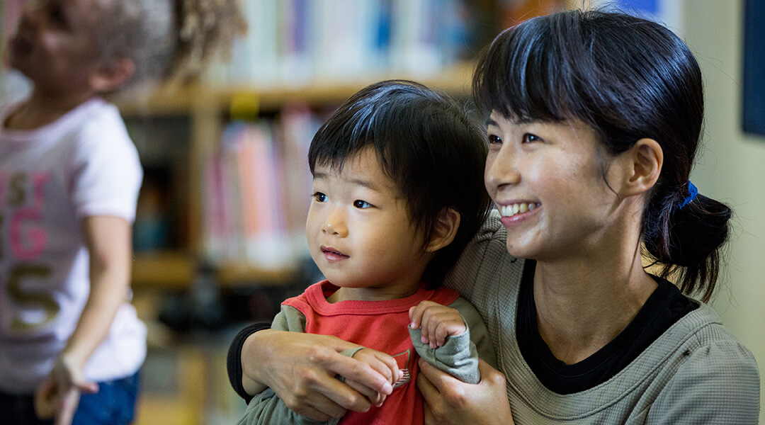 Caregiver and child smiling while watching a storytime program.