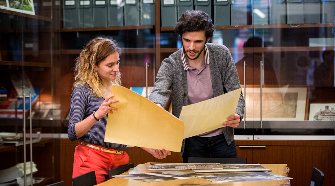 Two people looking at research materials in a library.