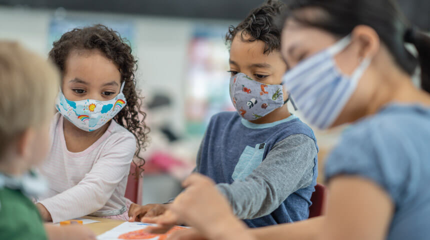 Three children wearing masks engaged in an art activity.