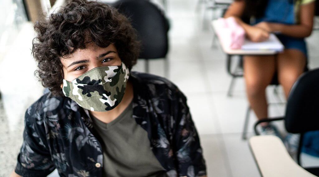 Teen wearing face mask sitting in classroom