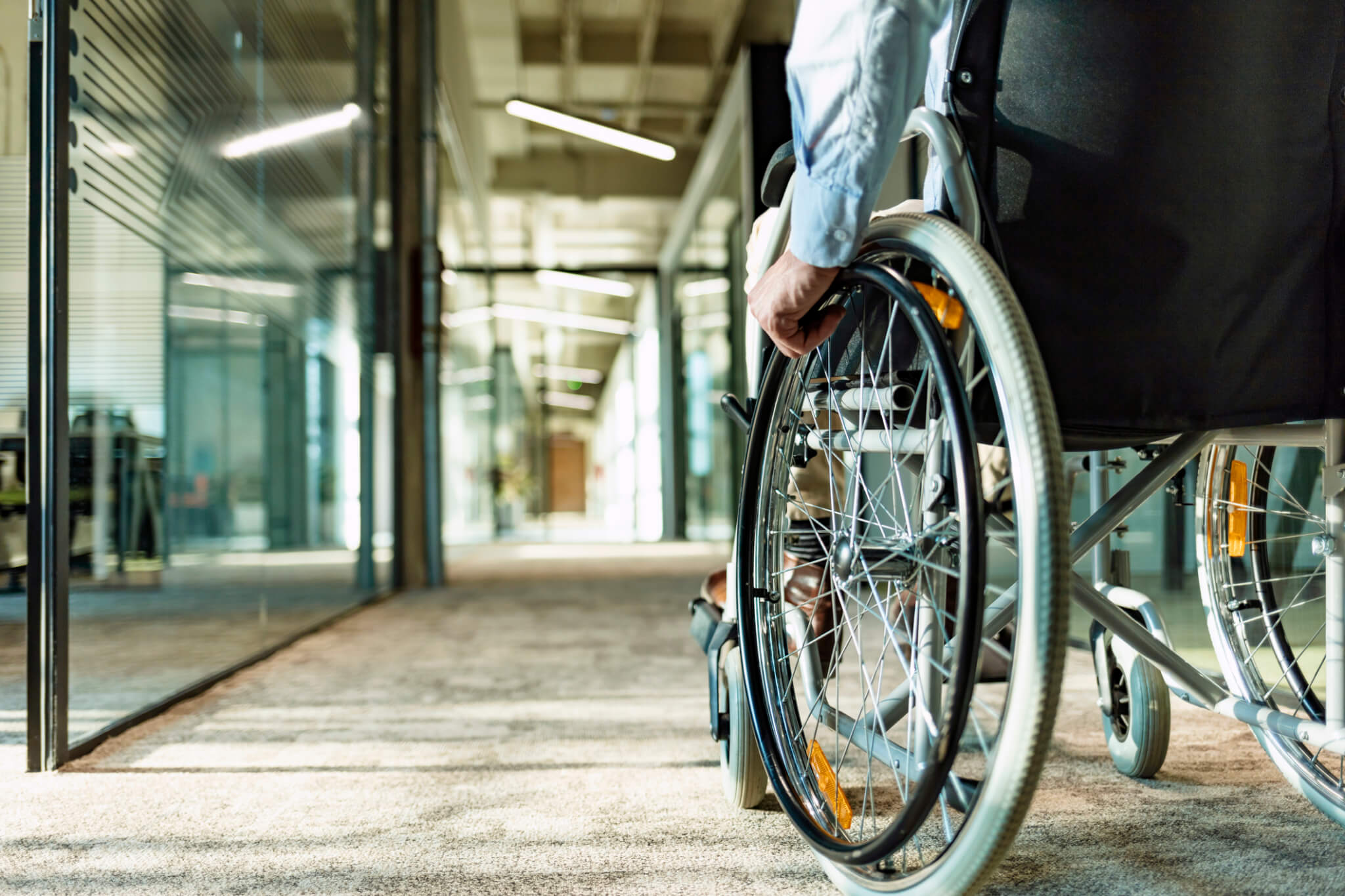 Person in wheelchair navigating down an office hallway.