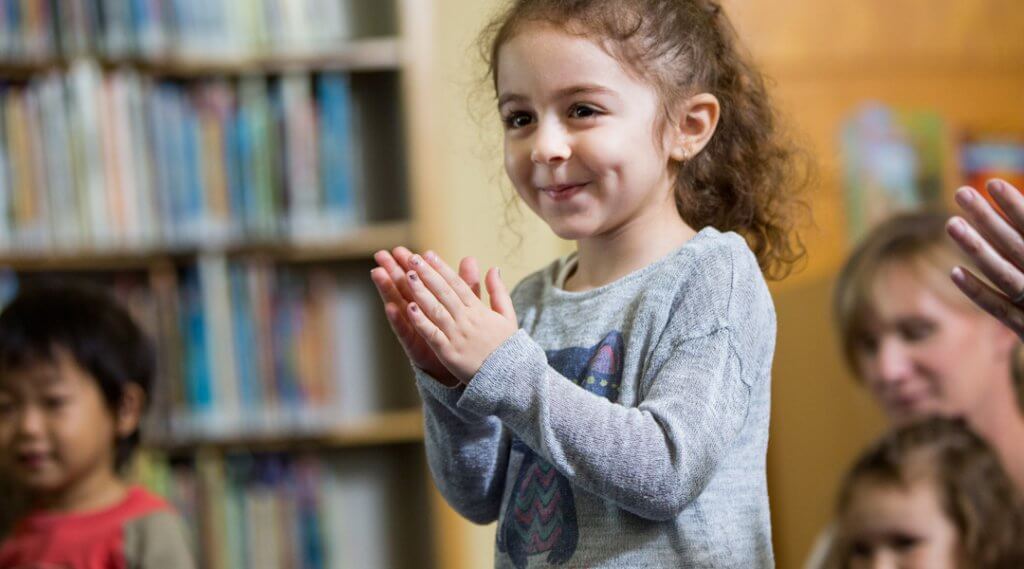 Toddler clapping and smiling at storytime.