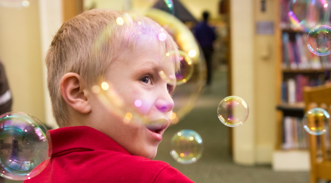 Smiling toddler surrounded by bubbles.