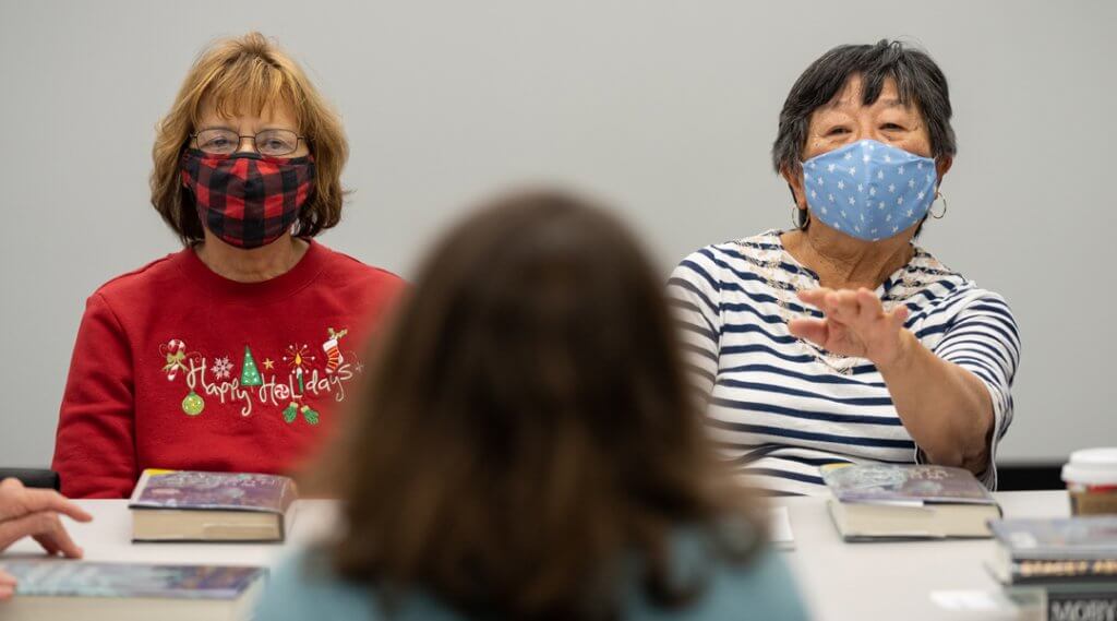 Adults wearing face masks attending a book club.