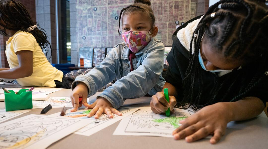Children wearing masks and coloring at the library.