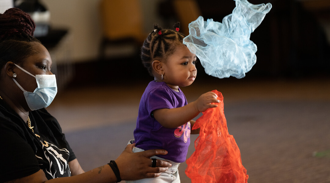 Baby and caregiver playing with scarves.