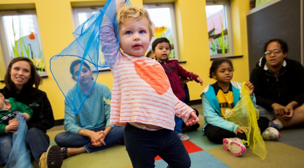Toddler playing with scarf in a storytime circle.