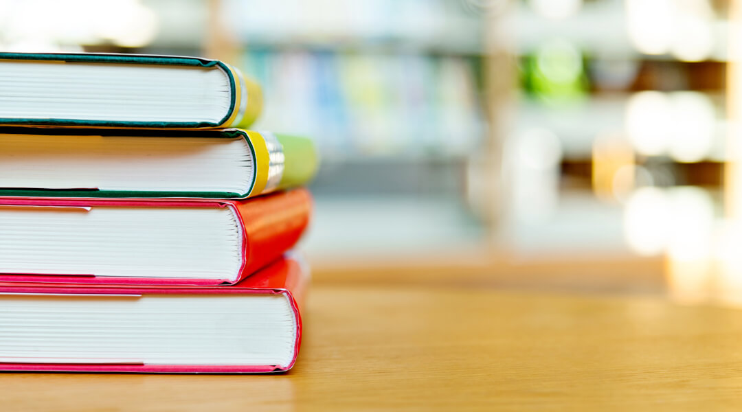 Stack of books with blurred library background.