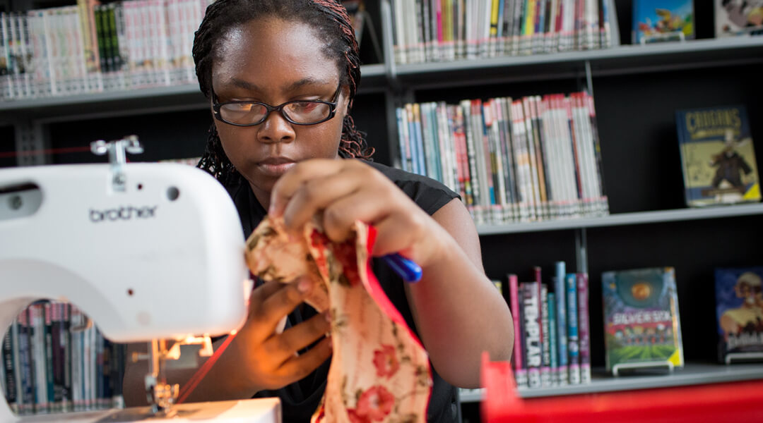 Teen using a sewing machine at the library.