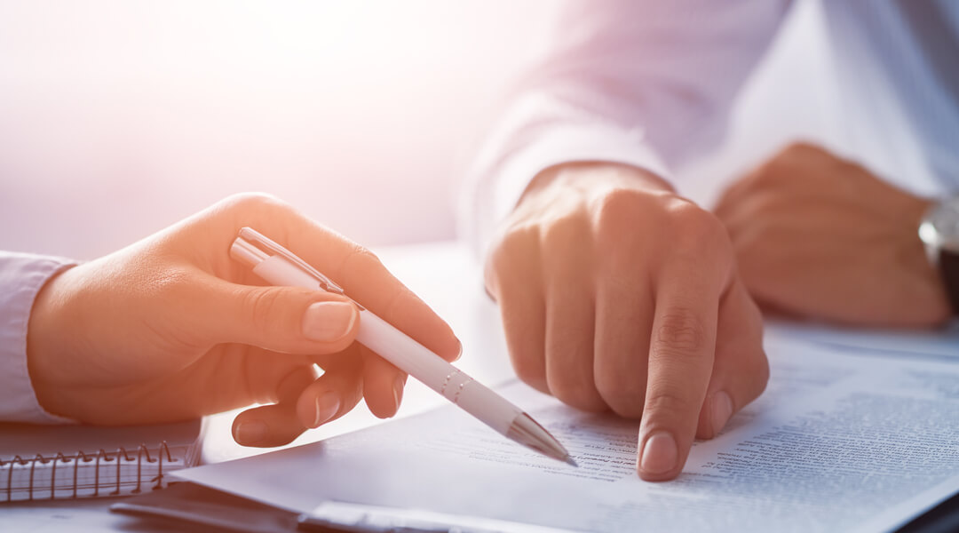 People reviewing paperwork with a pen.