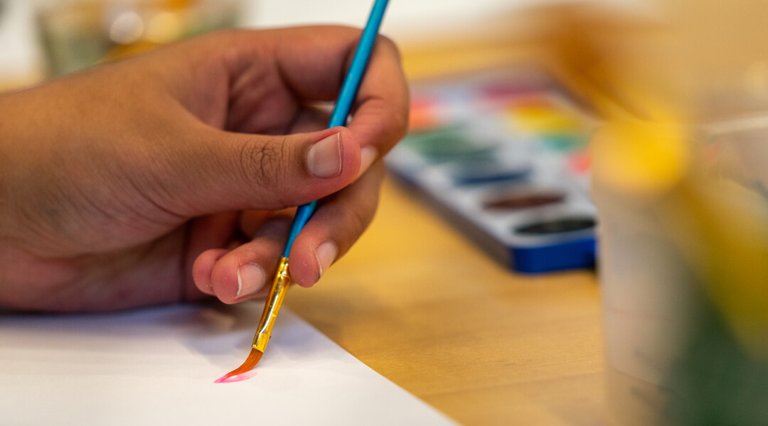 Close-up of a hand painting with watercolors.