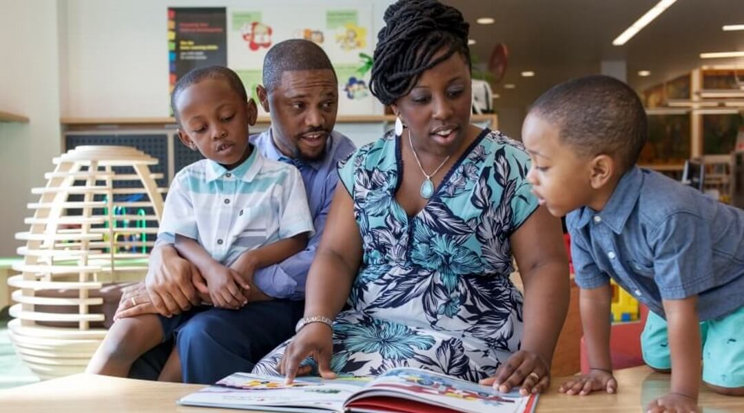 Parents and two young children read books together