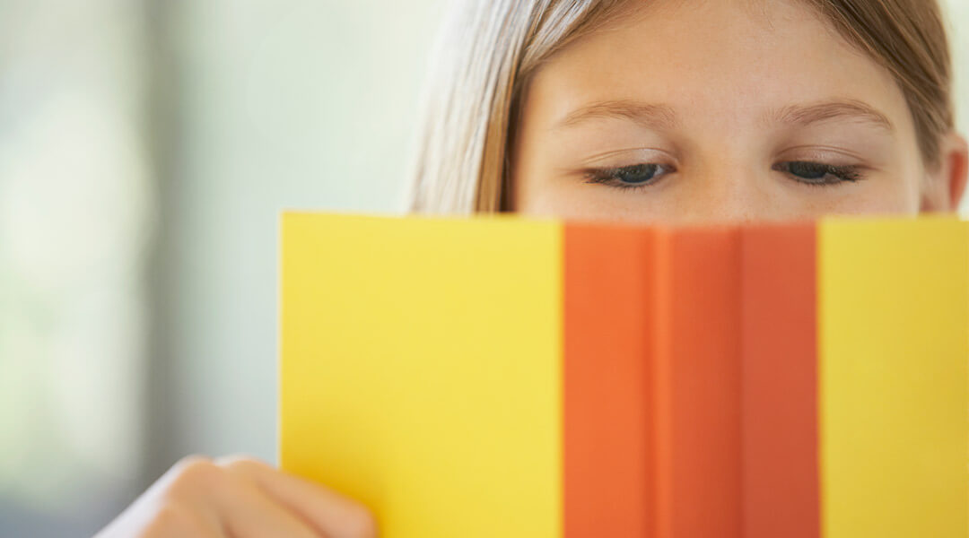 A close-up of a school-age child reading a book.