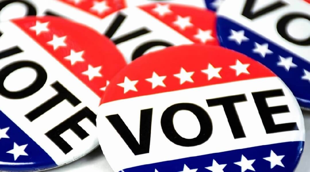 Close-up photo of red, white and blue "vote" pins