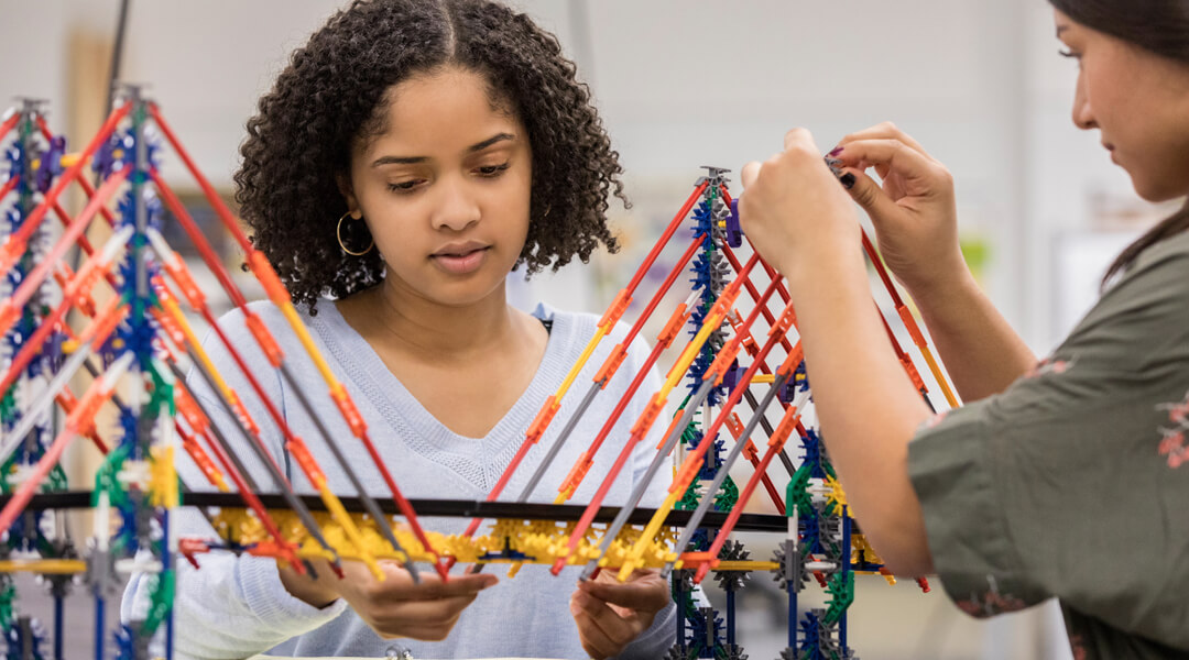 Two teens building a bridge out of K'Nex