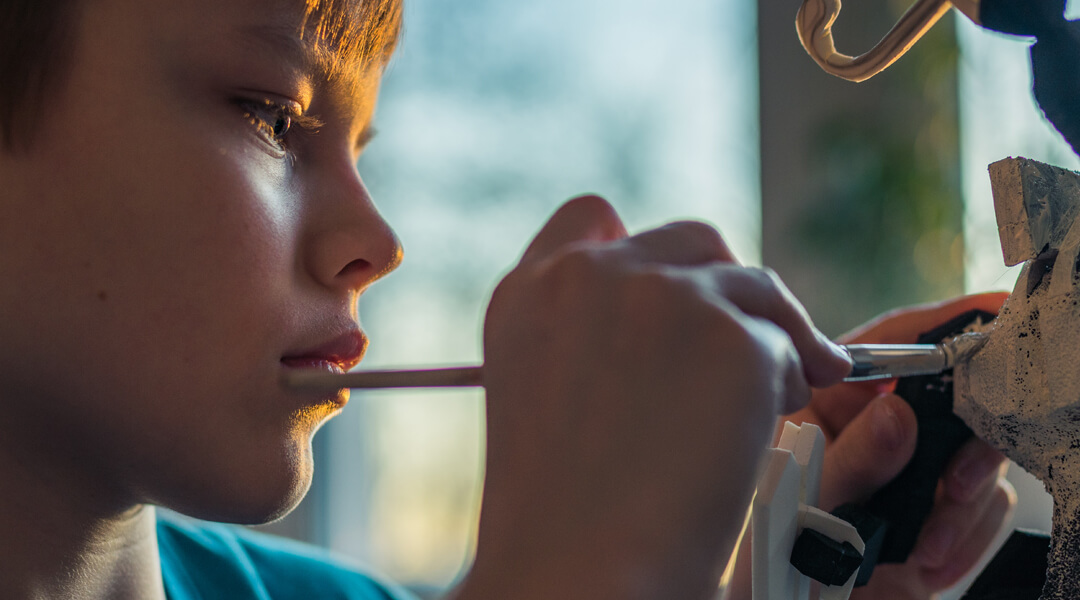 Kid painting a small model sculpture