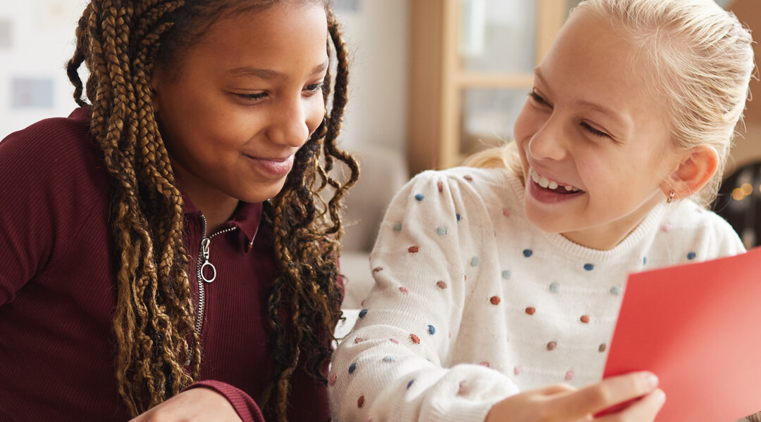 Two children sitting next to one another, smiling