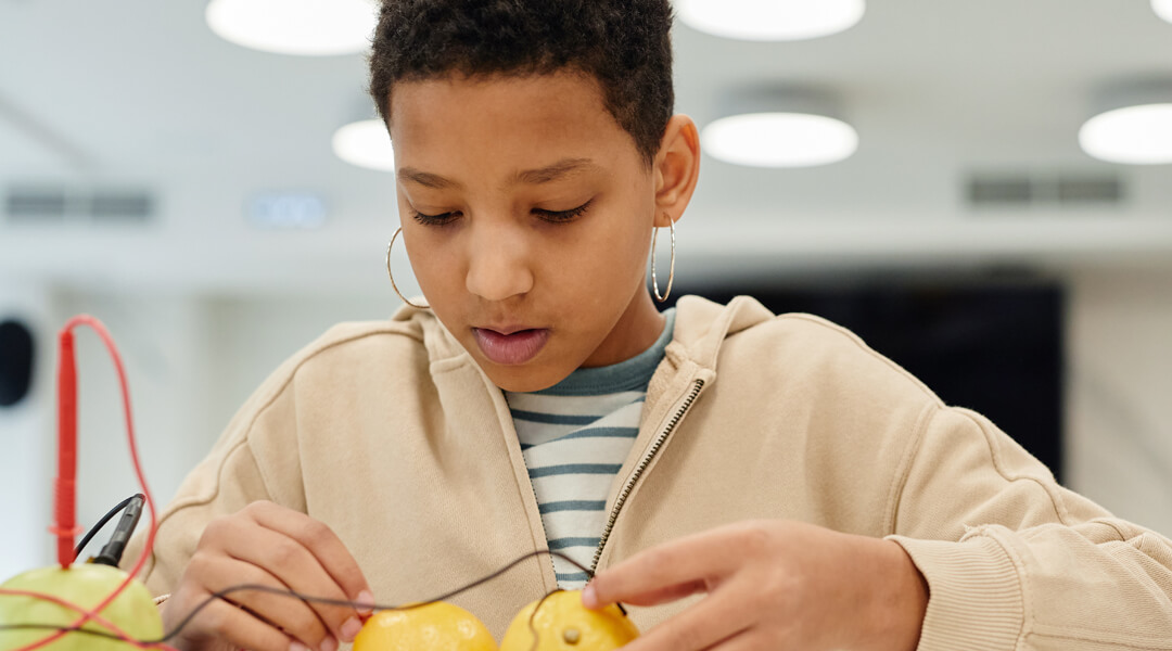 Teenager doing an experiment connecting wires into lemons