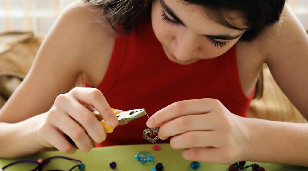 Teen using pliers to make a piece of metal jewelry
